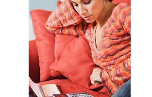 Young woman with her credit cards and cheque book on the couch, calculating her savings. 