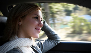 Une jeune femme au volant de sa voiture lors d'un après-midi ensoleillé. 