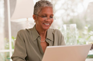 Femme portant des lunettes effectuant des opérations bancaires en ligne sur son ordinateur portatif.