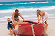 Image of family pushing boat on beach